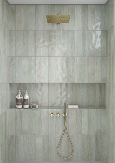 Shower wall in Village Hijau glossy 4x16 ceramic tile with a long recessed niche whose top and shelf line up with the grout lines