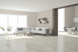 Modern living room with a white sofa, coffee table, porcelain wood look tile floor and decorative elements.