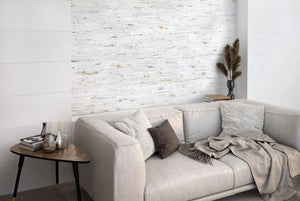 Gray sofa with decorative pillows and blankets in a room with a Thuy Blanco 3D Textured Ledger Look Porcelain Wall Tile