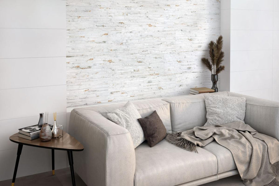 Gray sofa with decorative pillows and blankets in a room with a Thuy Blanco 3D Textured Ledger Look Porcelain Wall Tile