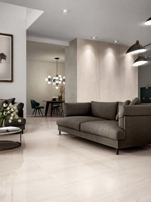 Modern living room with a gray sofa, dining area in the background, and large porcelain slabs for a seamless look.