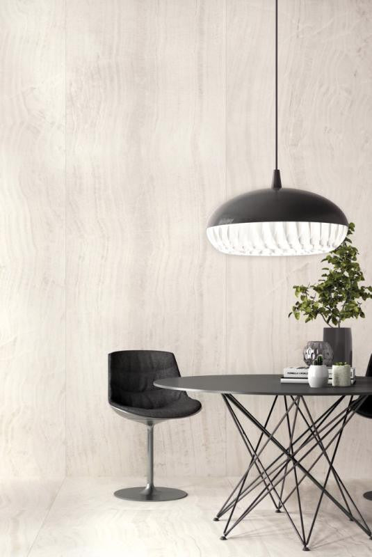 Modern dining area with a black pendant light, table, and chair against a seamless large porcelain slab wall.