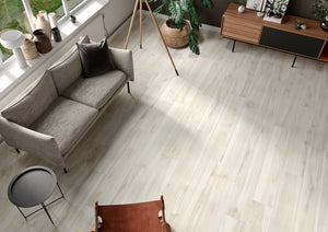 Wood-look porcelain floor tiles installed in a modern living room setting with a gray sofa, wooden sideboard, and plants.