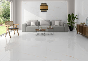 A modern living room featuring glossy white marble-look porcelain floor tiles with subtle gold veining, a light gray sofa, a wooden chair, and a large potted plant.