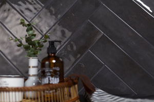 Bathroom setting with black tiled wall, basket, and bottles.