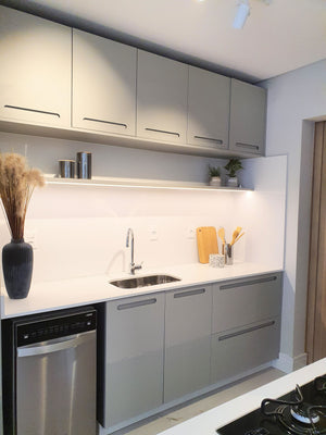 Modern kitchen cabinetry with light gray doors, white countertops, a built-in stainless steel dishwasher, open shelving, and a sink with a chrome faucet.